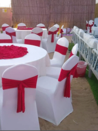 Beachside Event Setup with White Chairs & Red Sashes